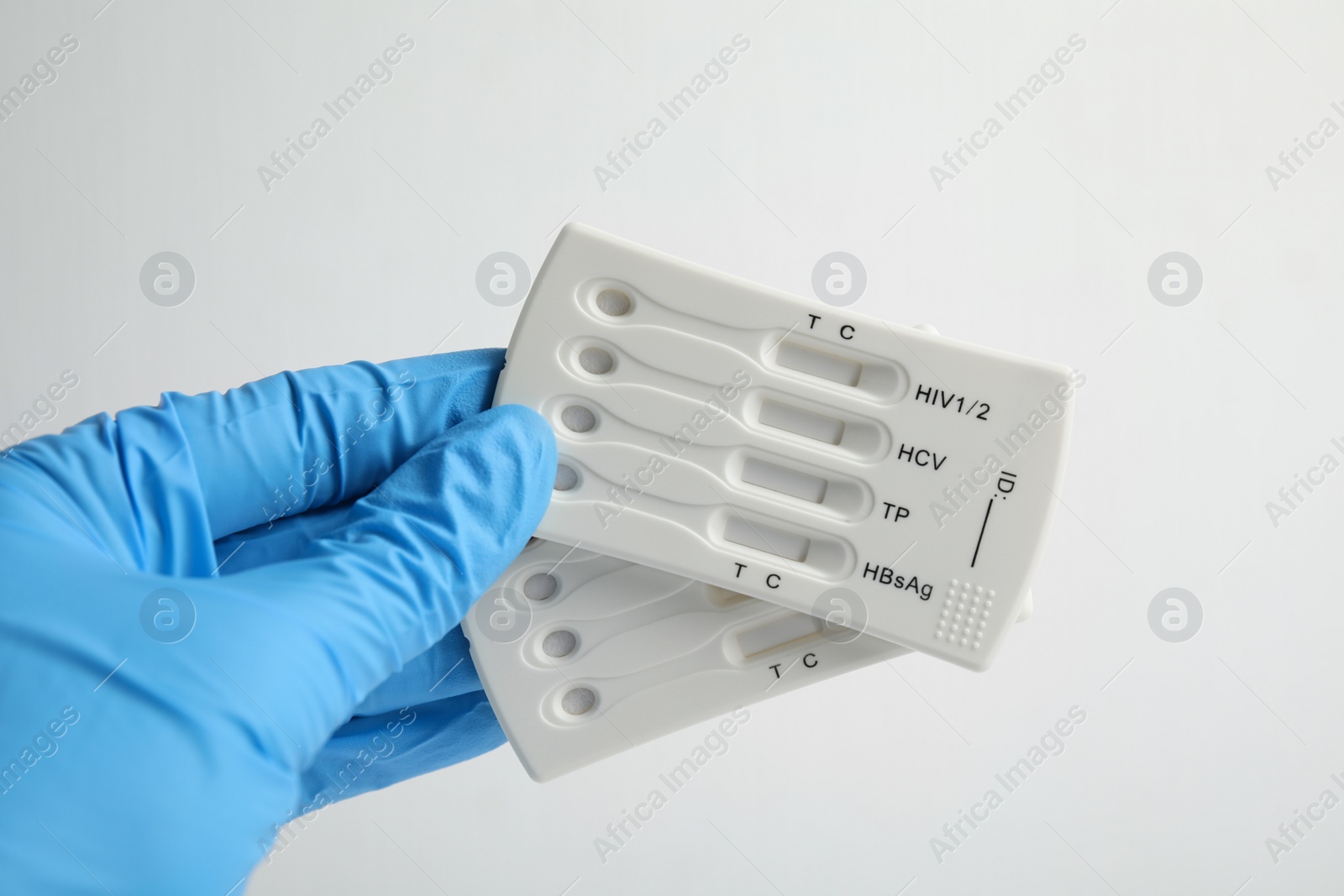 Photo of Doctor holding two disposable express tests for hepatitis on white background, closeup