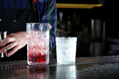 Photo of Barman making fresh alcoholic Red Russian cocktail on bar counter, closeup. Space for text