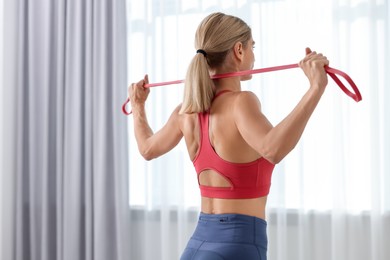 Photo of Fit woman doing exercise with fitness elastic band indoors