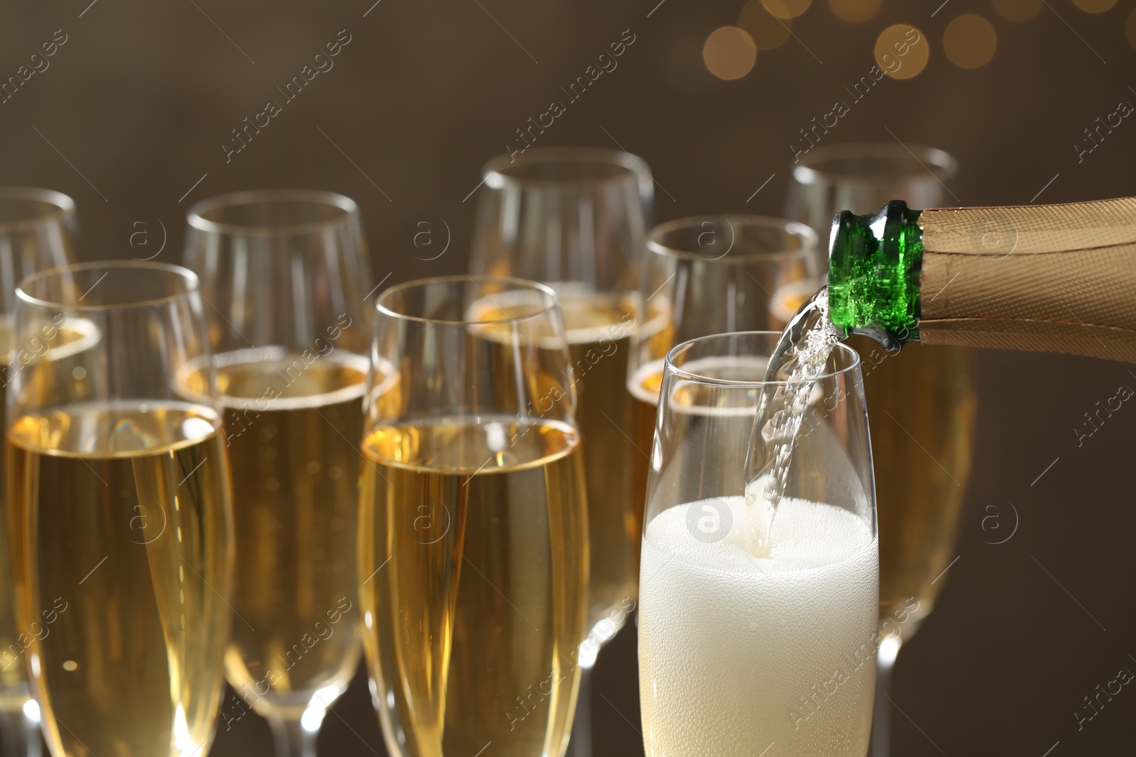 Photo of Pouring champagne into glasses on blurred background, closeup