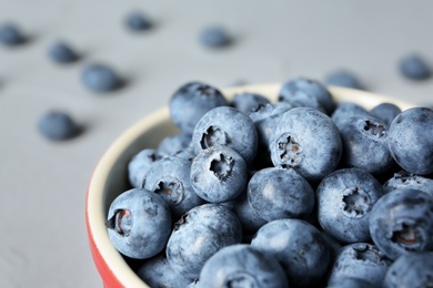 Photo of Crockery with juicy and fresh blueberries on color table, closeup