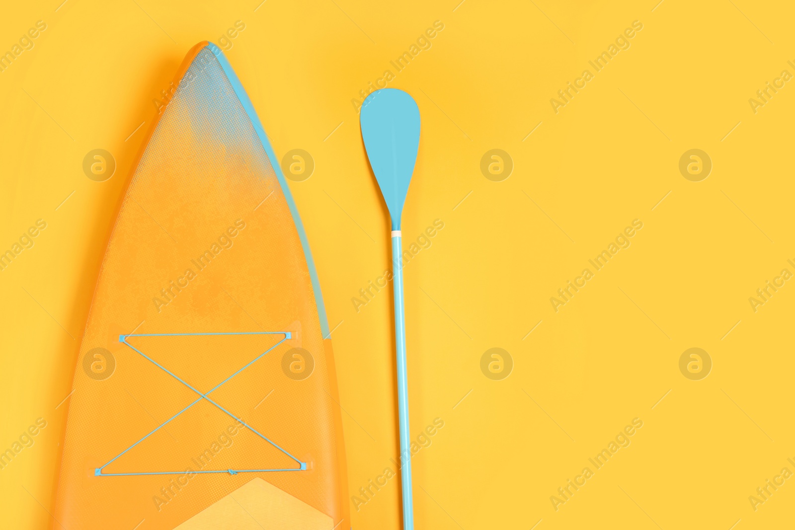 Photo of Board and paddle on orange background, flat lay with space for text. Standup paddleboarding (SUP)