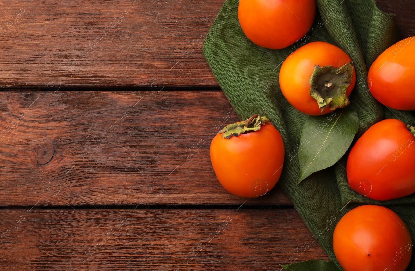 Photo of Delicious ripe persimmons on wooden table, flat lay. Space for text