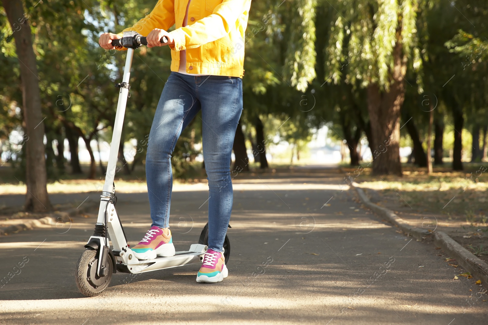 Photo of Woman riding electric kick scooter outdoors. Space for text