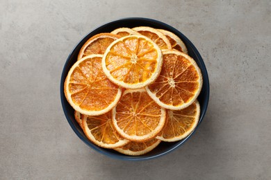 Bowl of dry orange slices on grey table, top view
