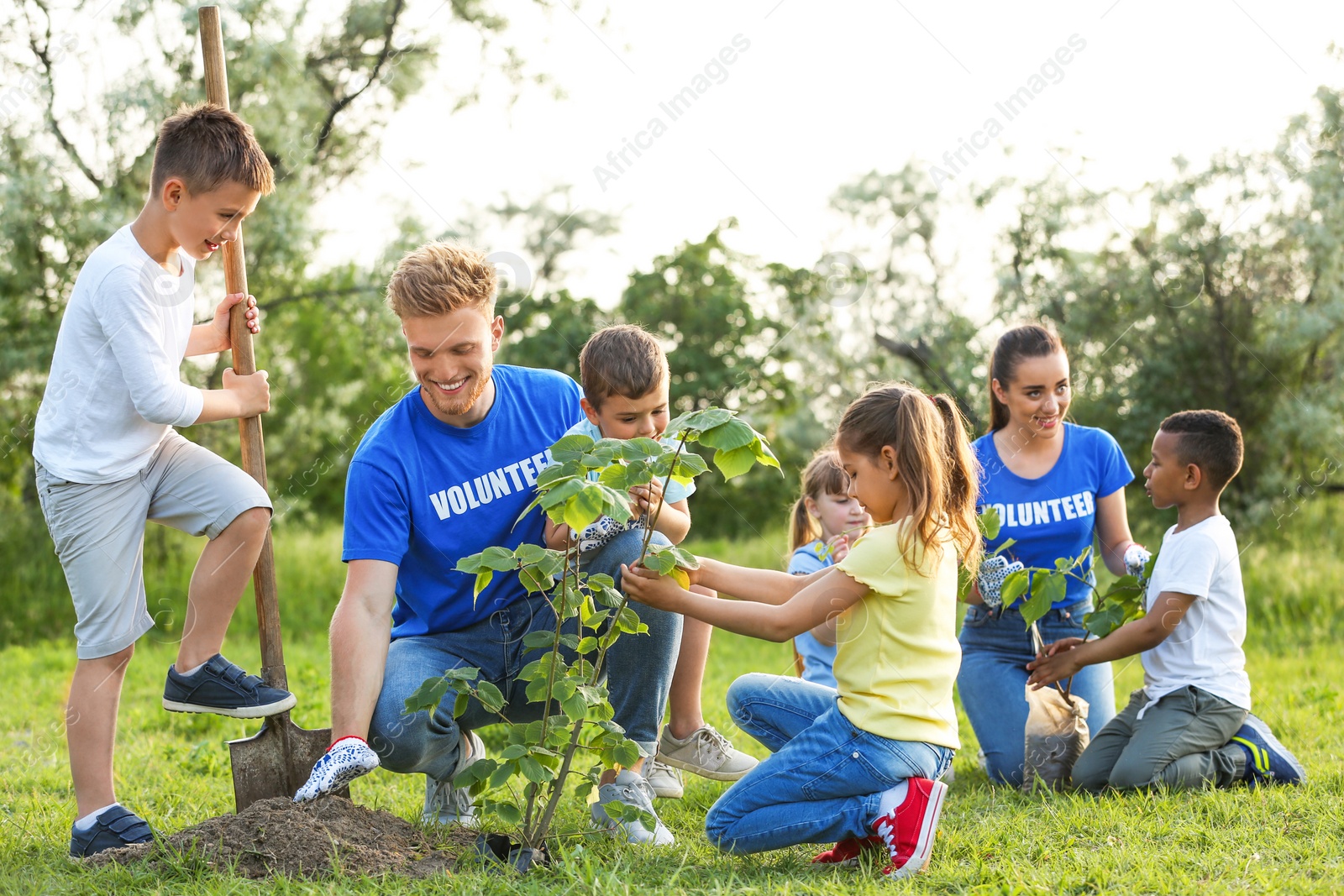 Photo of Kids planting trees with volunteers in park