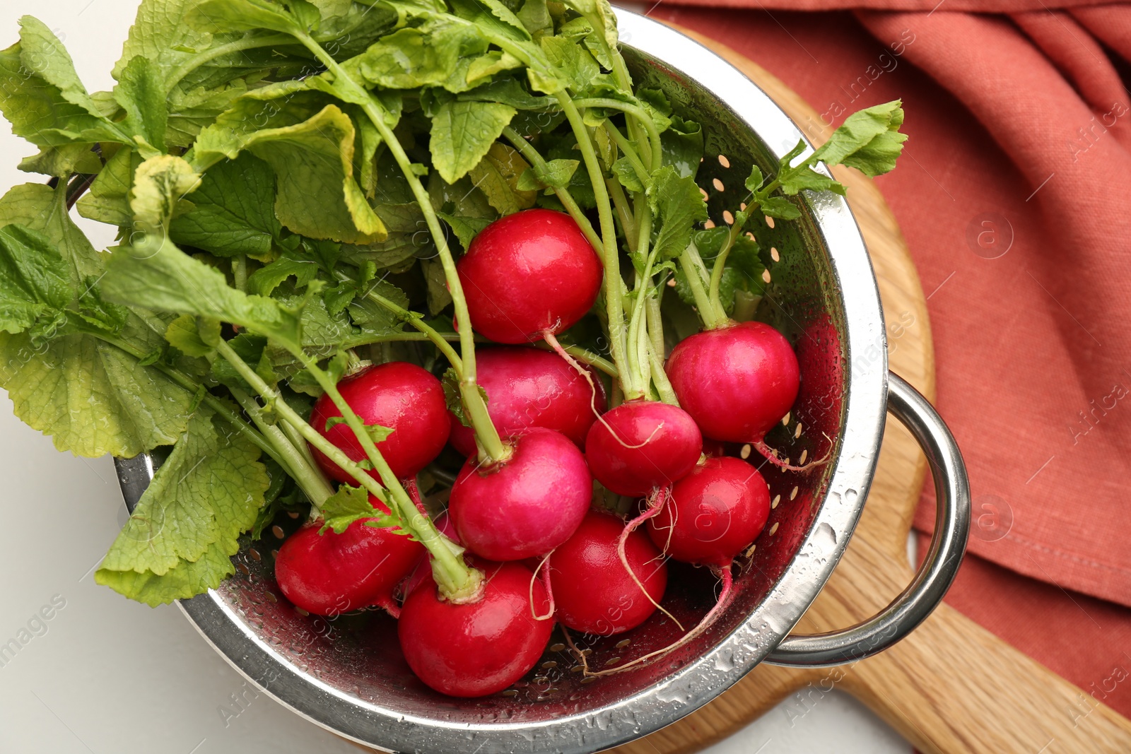 Photo of Wet radish in colander on white table, top view