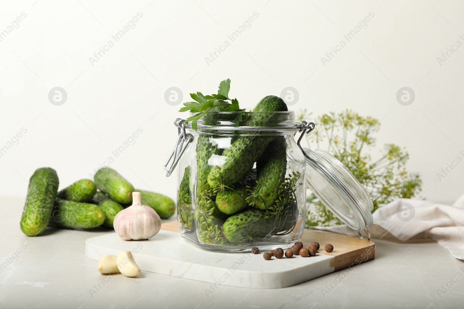 Photo of Pickling jar with fresh cucumbers on light table