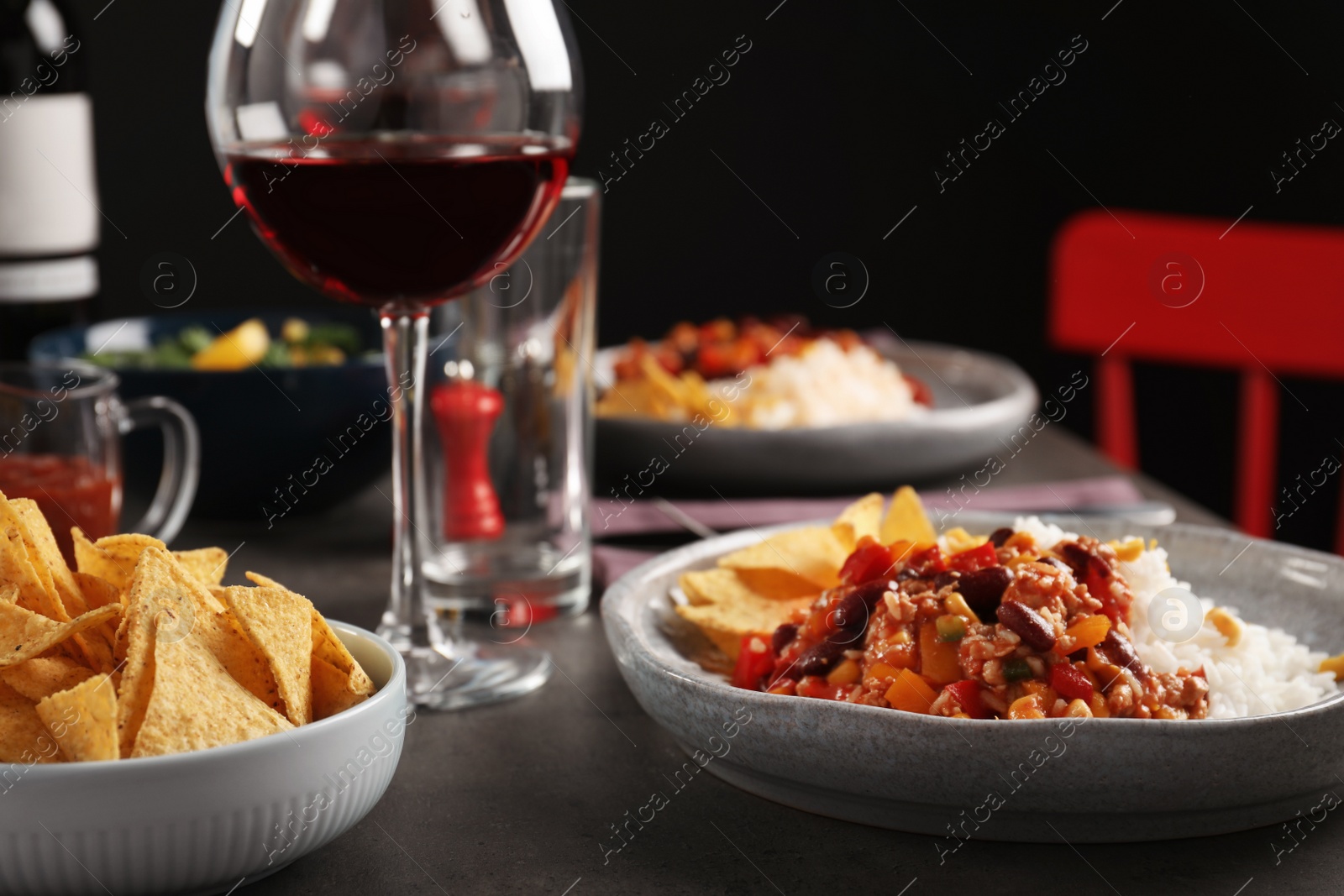 Photo of Tasty chili con carne served with rice on gray table. Dinner in restaurant