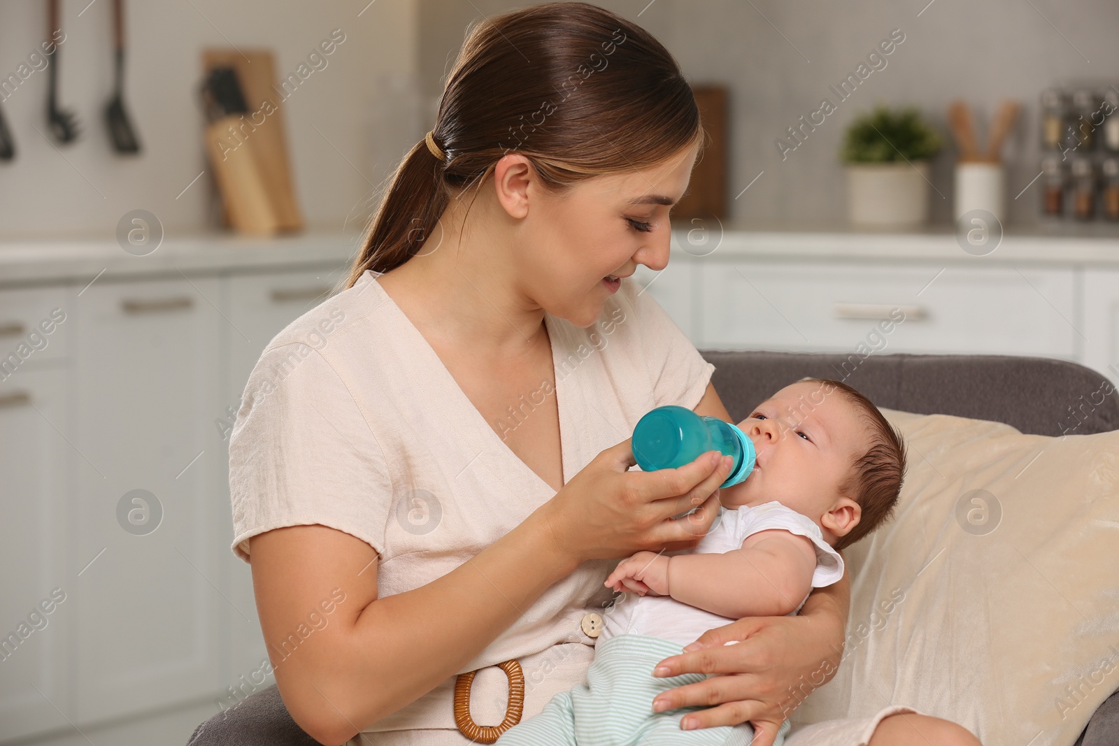 Photo of Mother feeding her cute child with infant formula indoors