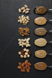 Tasty nut butters in spoons and raw nuts on dark gray textured table, flat lay