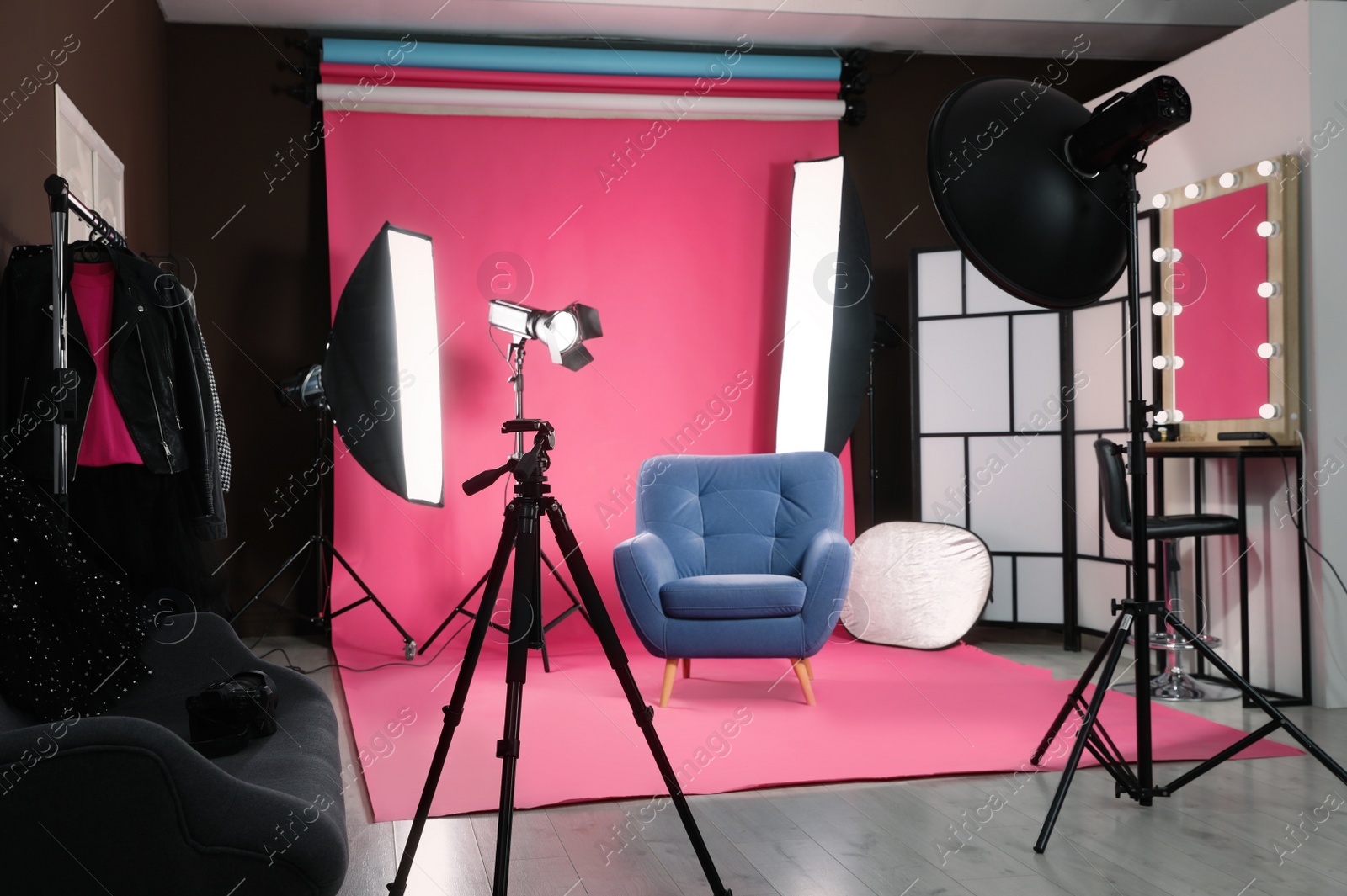 Photo of Stylish blue armchair in photo studio with professional equipment