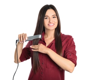 Young woman using hair iron on white background