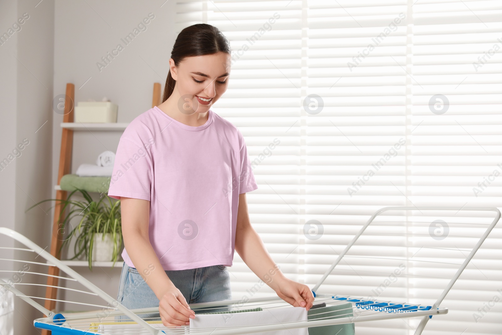 Photo of Woman hanging different apparel on clothes airer in bathroom