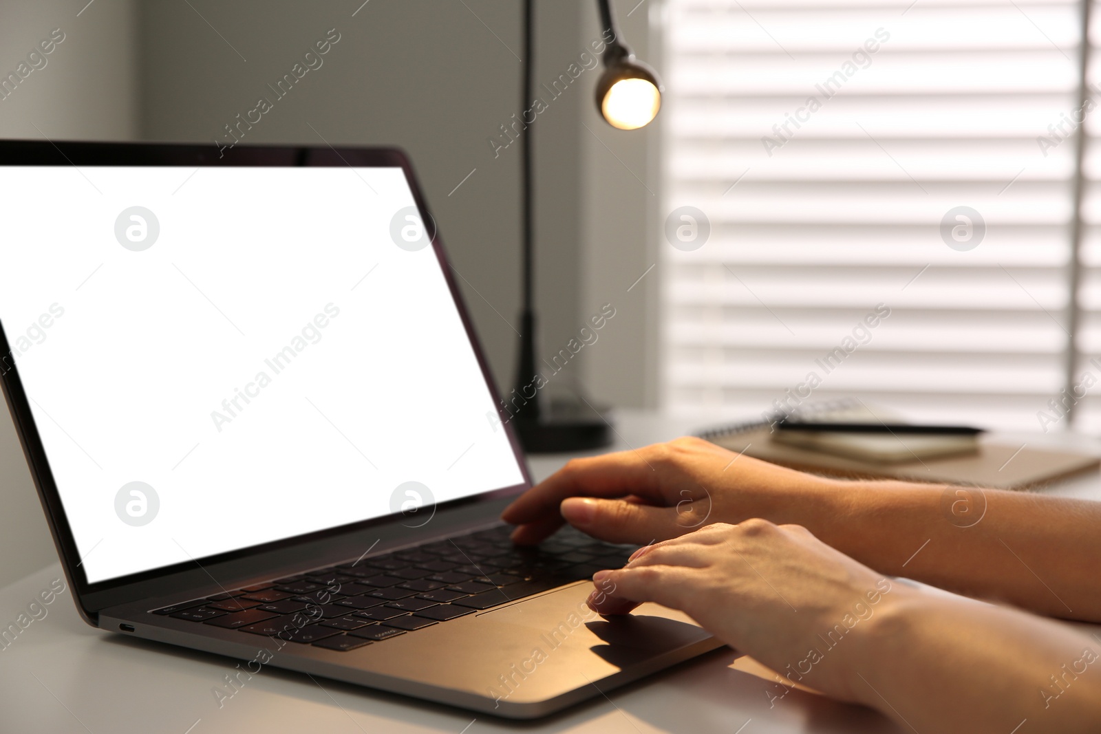 Photo of Woman working with modern laptop at white table, closeup