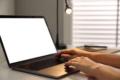 Photo of Woman working with modern laptop at white table, closeup