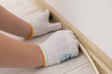 Photo of Man installing plinth on laminated floor in room, closeup