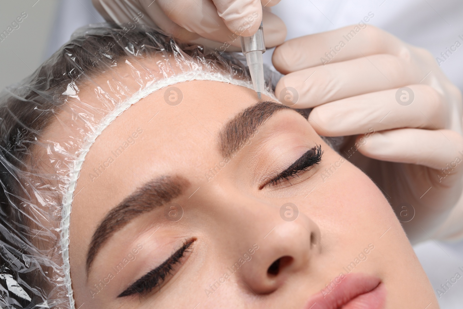 Photo of Young woman during procedure of permanent eyebrow makeup, closeup