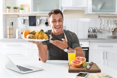 Photo of Portrait of food blogger with laptop in kitchen. Online broadcast