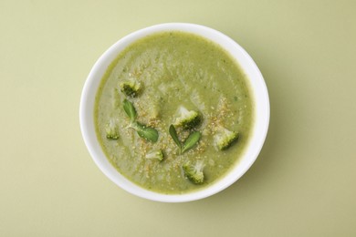 Delicious broccoli cream soup on olive background, top view