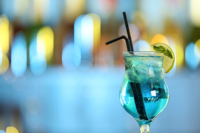 Photo of Glass of fresh alcoholic cocktail against blurred background. Space for text