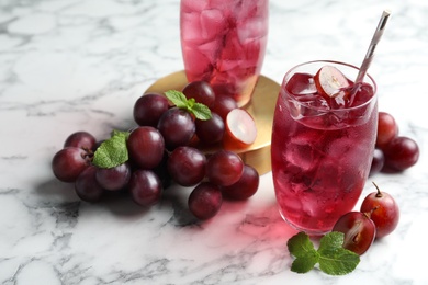 Photo of Delicious grape soda water with mint and berries on white marble table. Refreshing drink