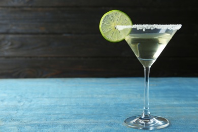 Glass of Lime Drop Martini cocktail on light blue wooden table. Space for text