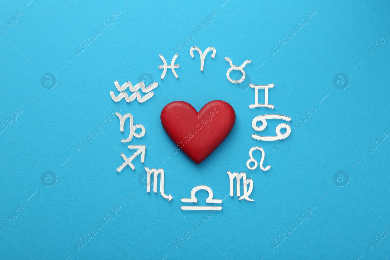 Photo of Zodiac signs and heart on light blue background, flat lay