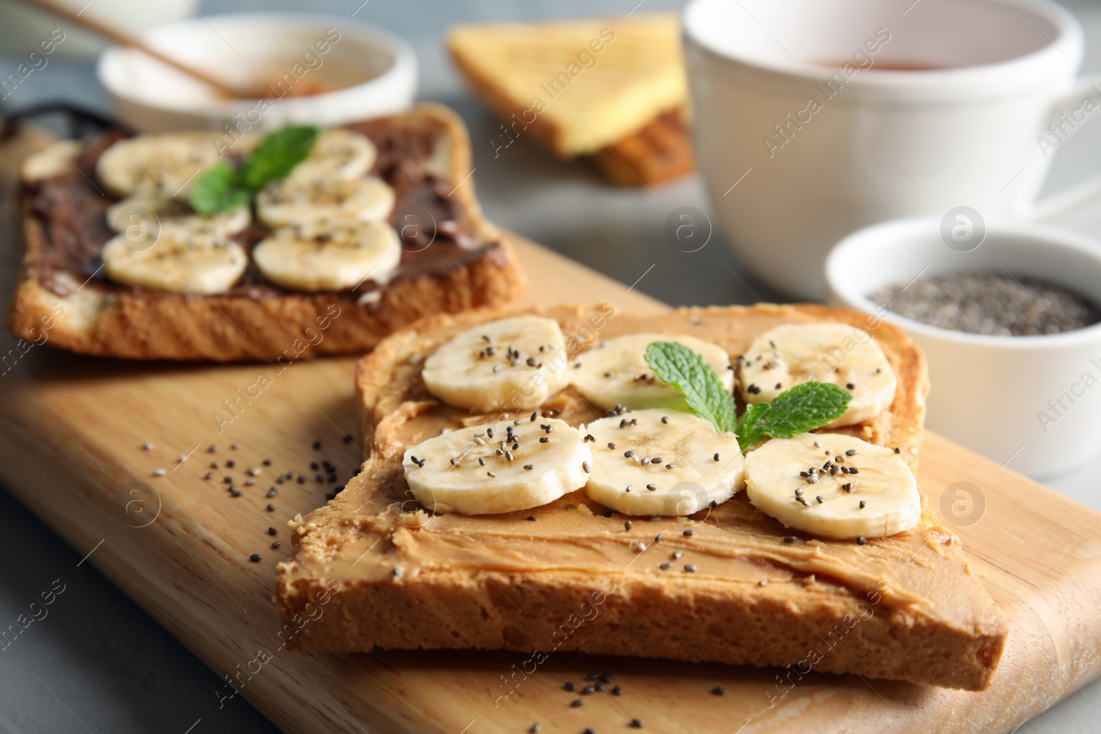 Photo of Tasty toasts with banana, mint and chia seeds on wooden board
