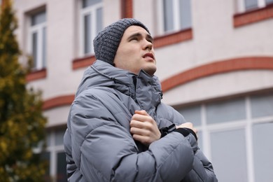 Photo of Sick young man in warm clothes on city street