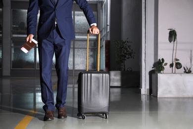 Photo of Businessman with black travel suitcase in airport. Space for text