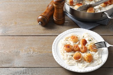 Photo of Delicious scallop pasta served on wooden table. Space for text