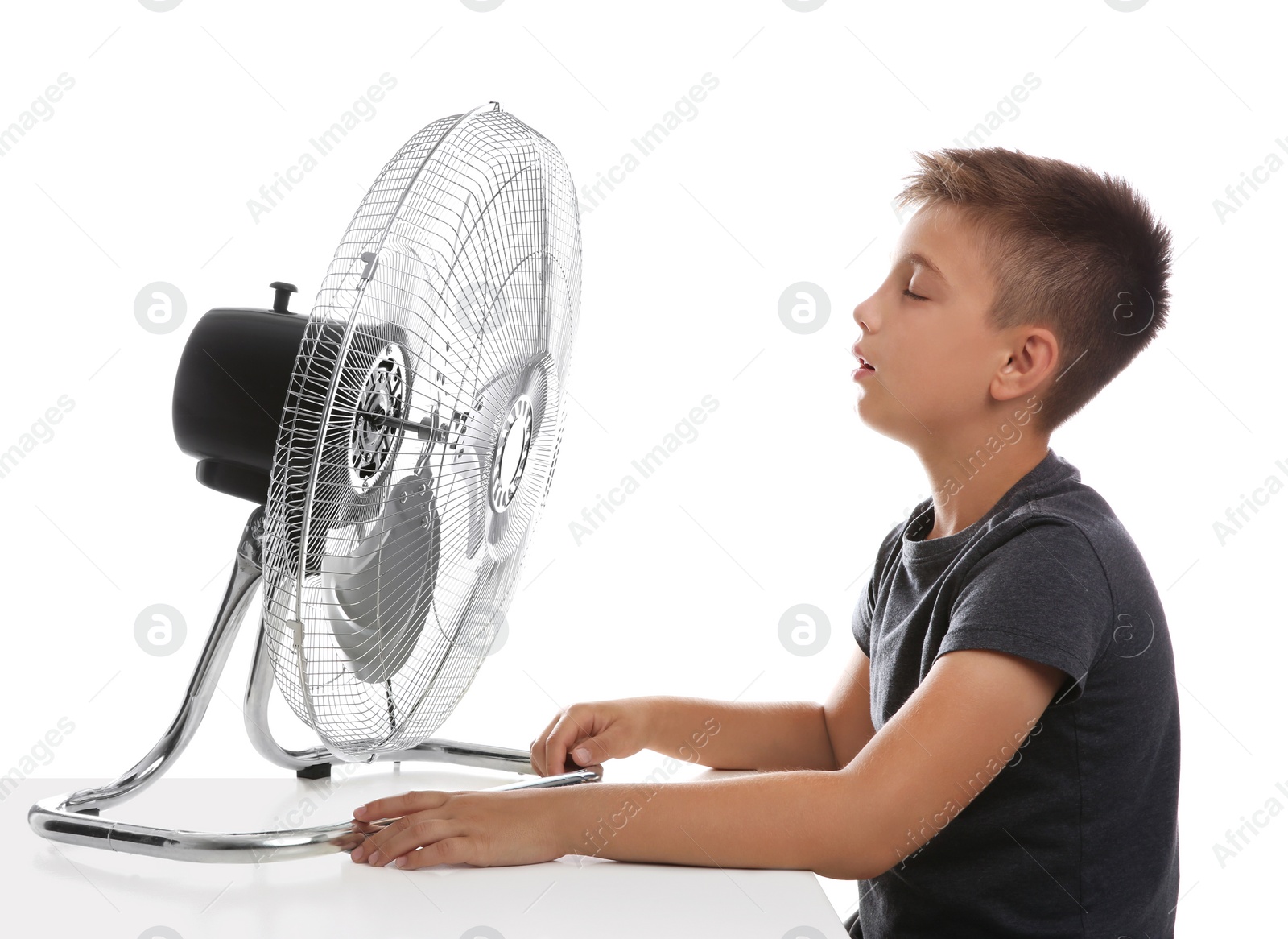 Photo of Little boy enjoying air flow from fan on white background. Summer heat