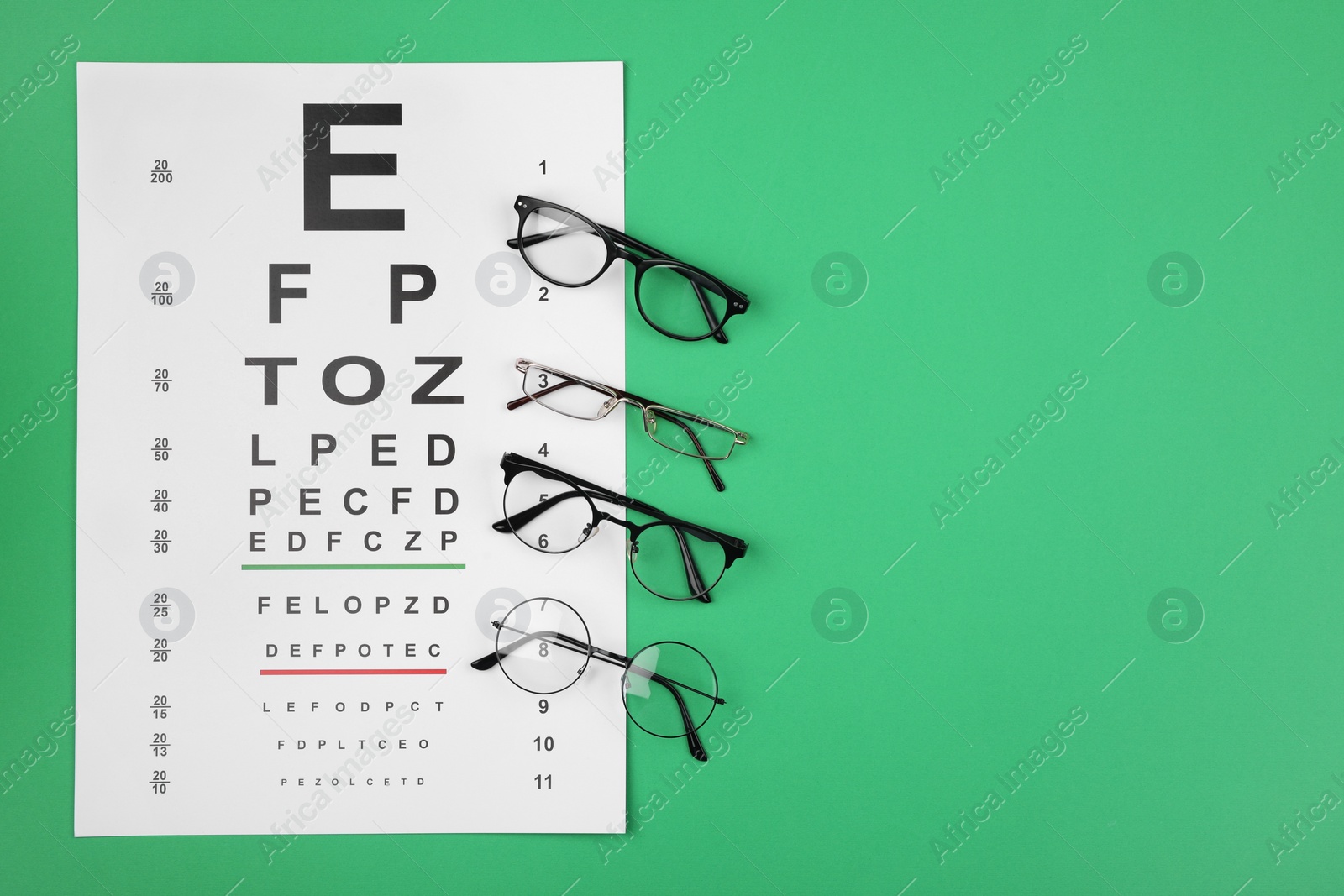 Photo of Vision test chart and glasses on green background, flat lay. Space for text