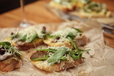 Delicious bruschettas with beef and cheese on table, closeup