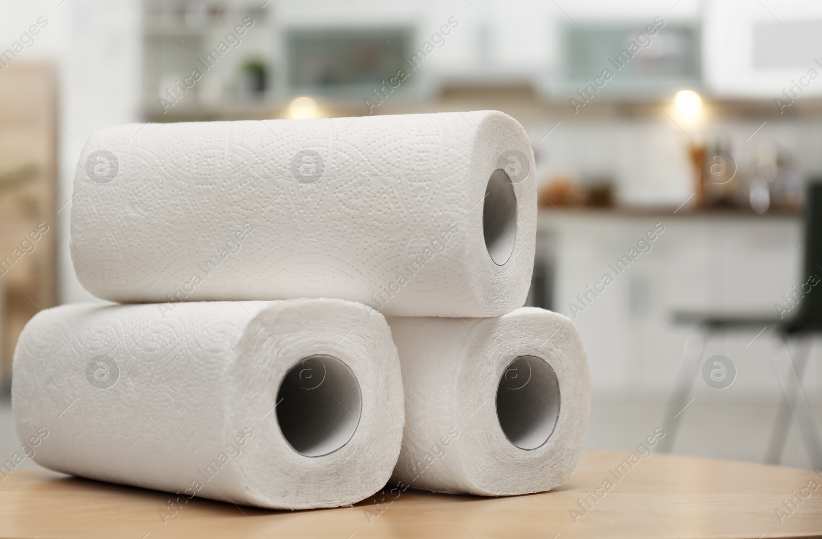 Photo of Rolls of paper towels on table in kitchen, space for text