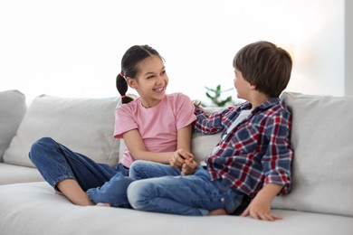 Photo of Happy brother and sister spending time together on sofa at home
