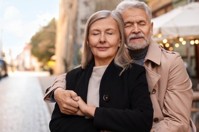Photo of Portrait of affectionate senior couple on city street, space for text