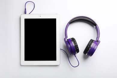 Photo of Stylish headphones and modern tablet on white background, top view. Space for text