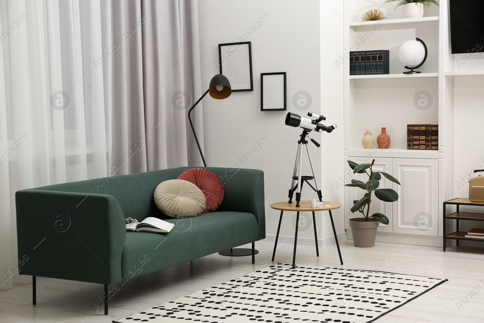 Photo of Tripod with modern telescope on table in living room