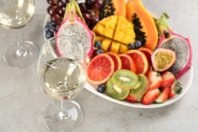 Delicious exotic fruits and wine on grey table