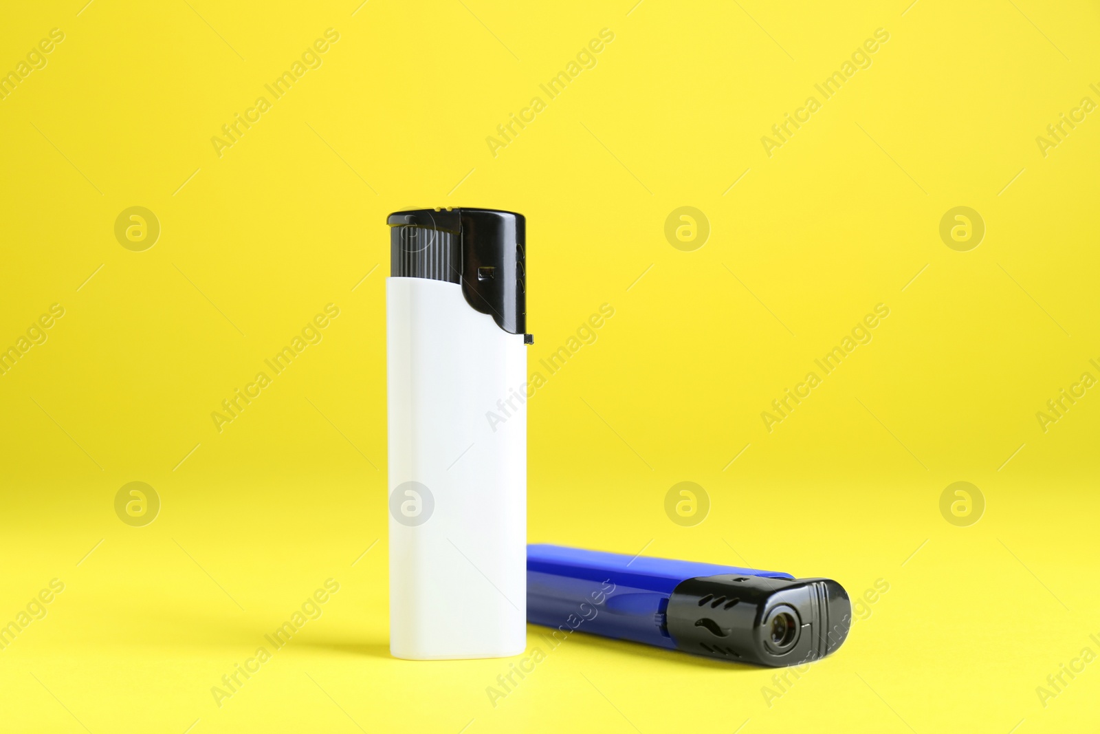 Photo of Stylish small pocket lighters on yellow background