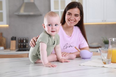 Photo of Happy young woman and her cute little baby cooking together in kitchen