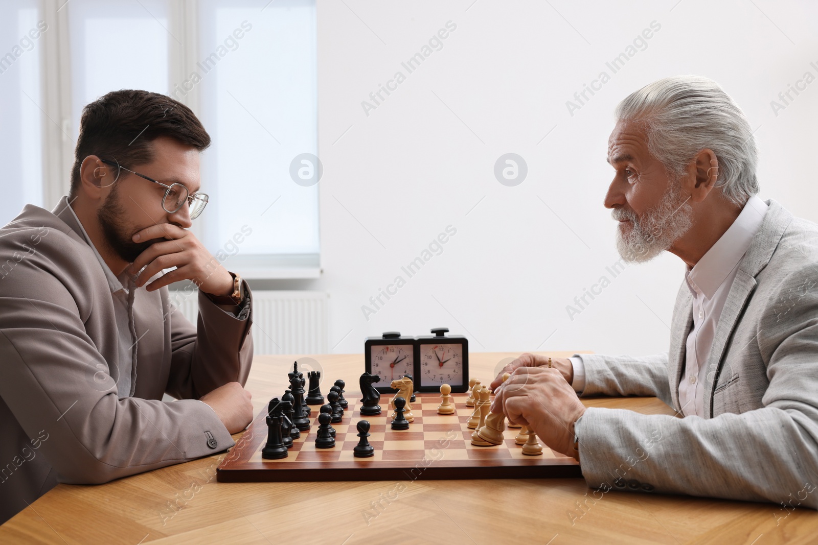 Photo of Men playing chess during tournament at table indoors