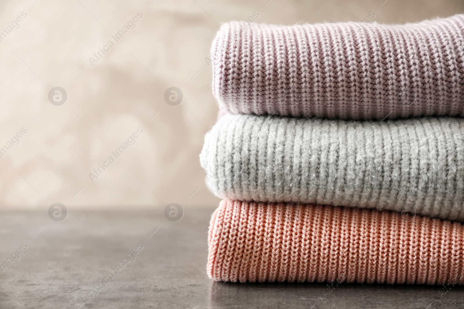 Photo of Stack of warm knitted clothes on table