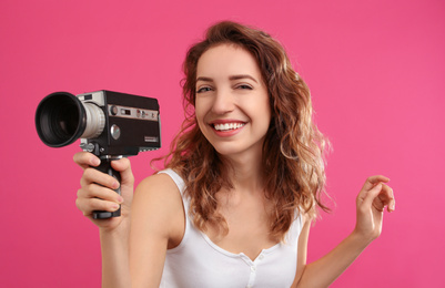 Beautiful young woman with vintage video camera on crimson background