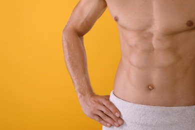 Photo of Shirtless man with slim body and towel wrapped around his hips on yellow background, closeup