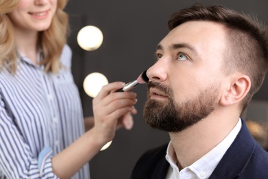 Photo of Professional makeup artist working with client in dressing room