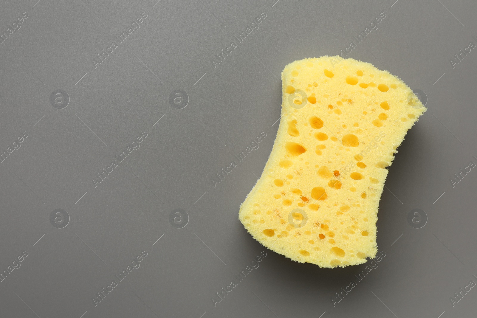 Photo of New yellow sponge on grey background, top view. Space for text