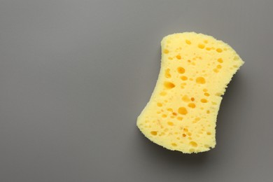 New yellow sponge on grey background, top view. Space for text